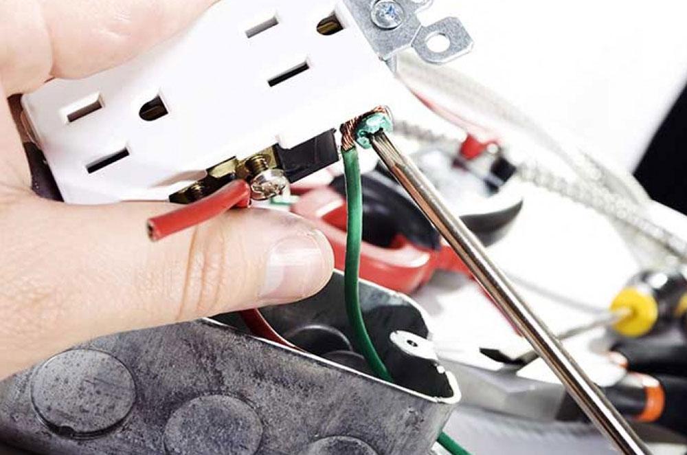 an electrician working on an electrical outlet