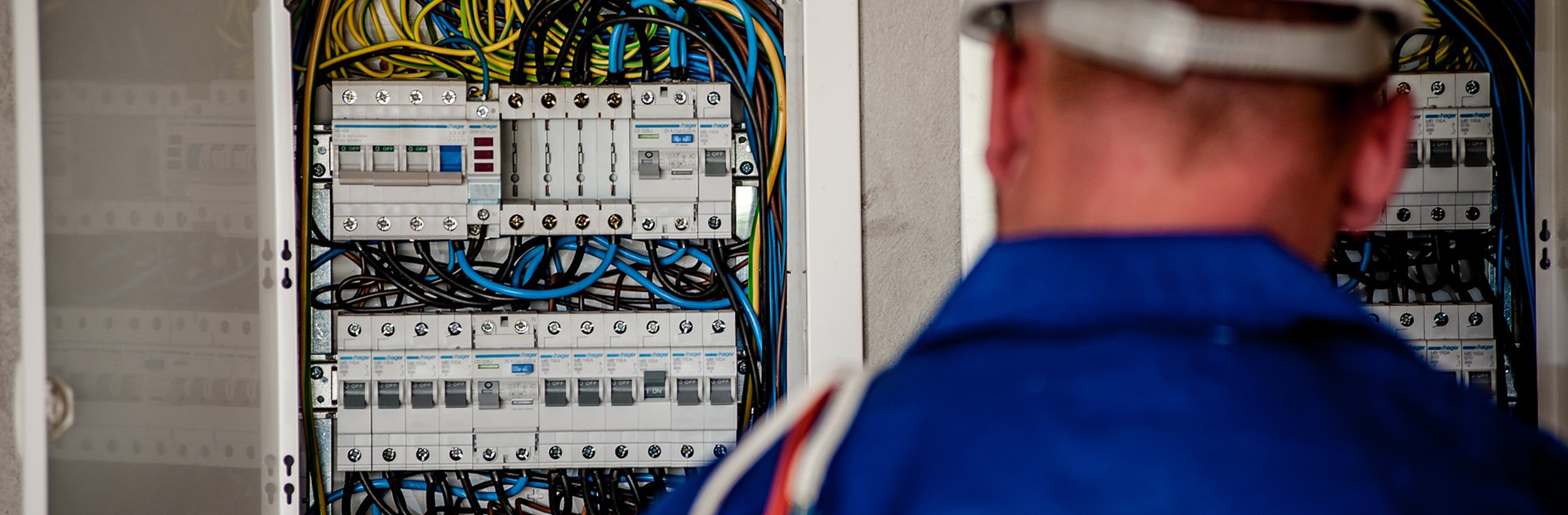 electrician wearing a blue shirt working on an electrical panel